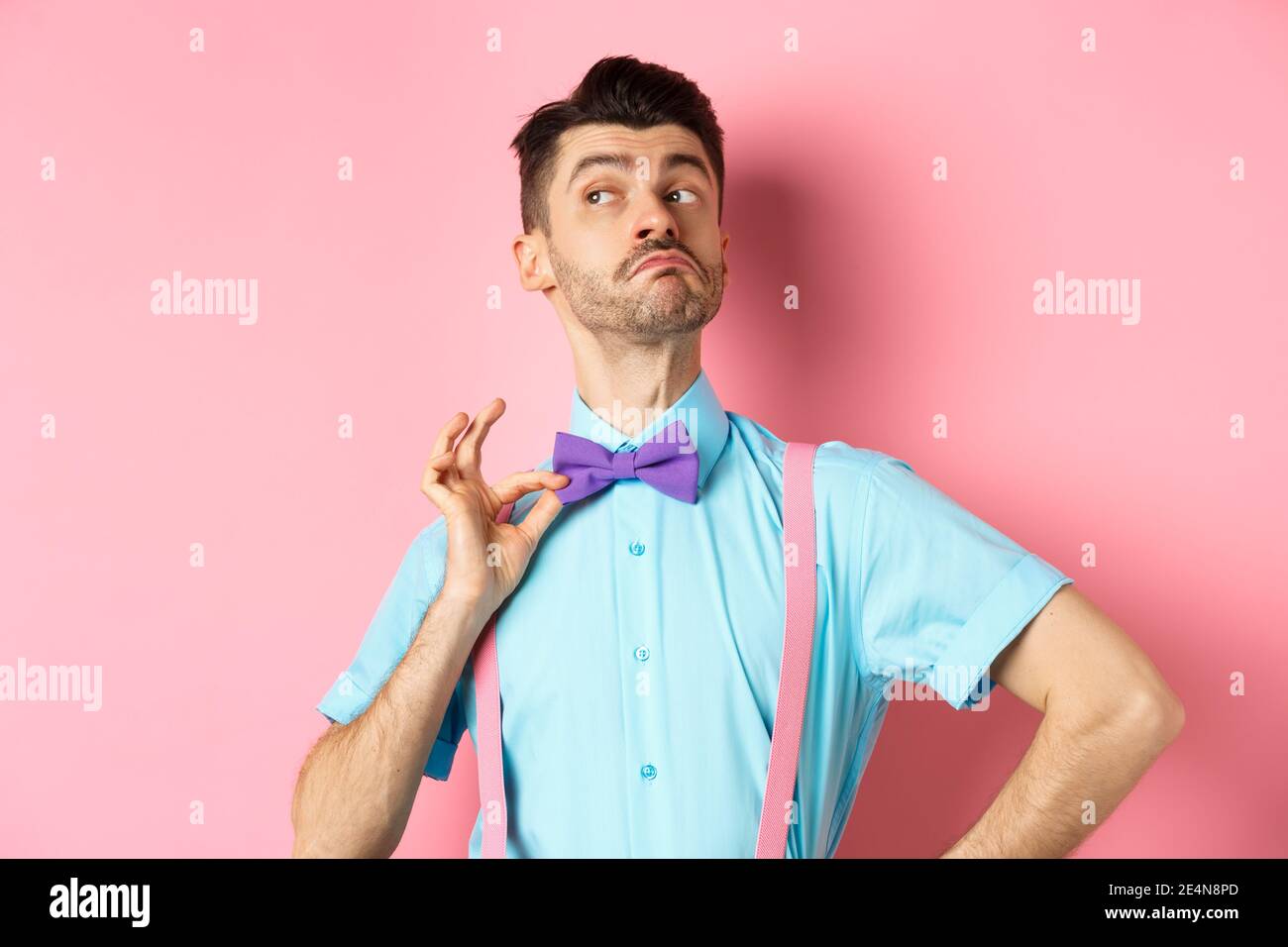 Image d'un drôle d'homme qui élève le menton et ajuste le noeud papillon,  se tenant confiant et sassy sur fond rose, en regardant à gauche Photo  Stock - Alamy