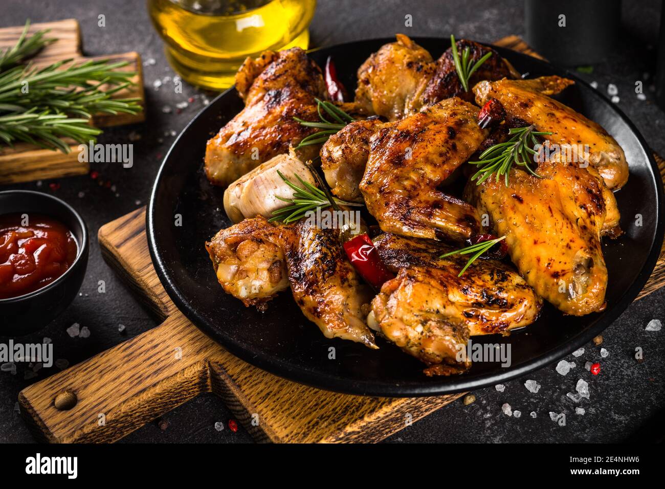 Ailes de poulet grillées aux épices dans une assiette noire. Banque D'Images