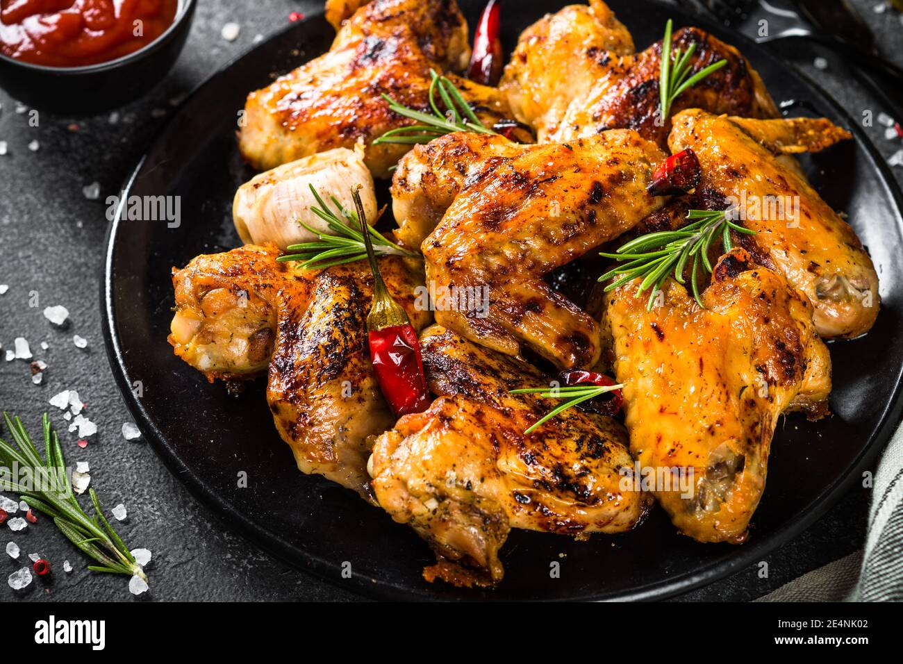 Ailes de poulet grillées aux épices dans une assiette noire. Banque D'Images