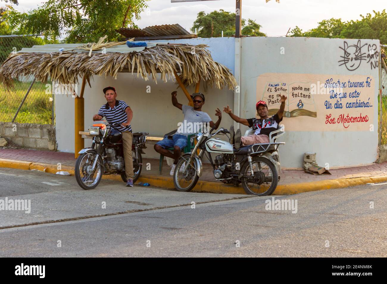 Trois hommes se détendent à l'ombre à un arrêt de bus à El Higuerito, République dominicaine. Banque D'Images