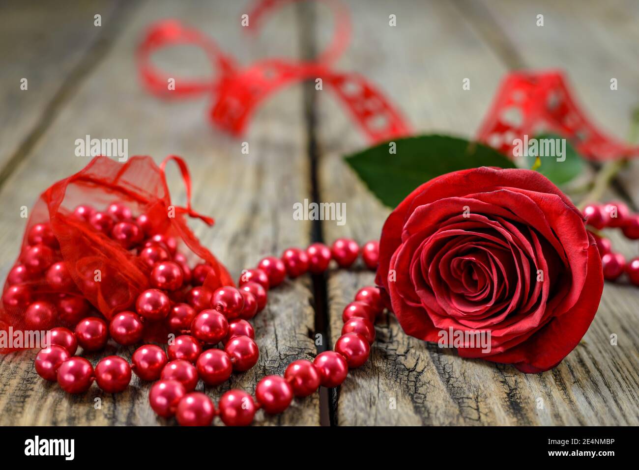 Rose rouge et corde de perles rouges sur une ancienne table en bois. Mise au point sélective. Banque D'Images