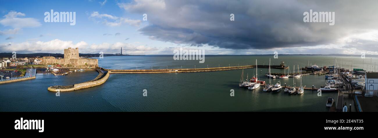 Carrickfergus près de Belfast, Irlande du Nord, Royaume-Uni. Large panorama du château normand médiéval, marina avec yachts, port avec brise-lames et Belfast Lugh Banque D'Images