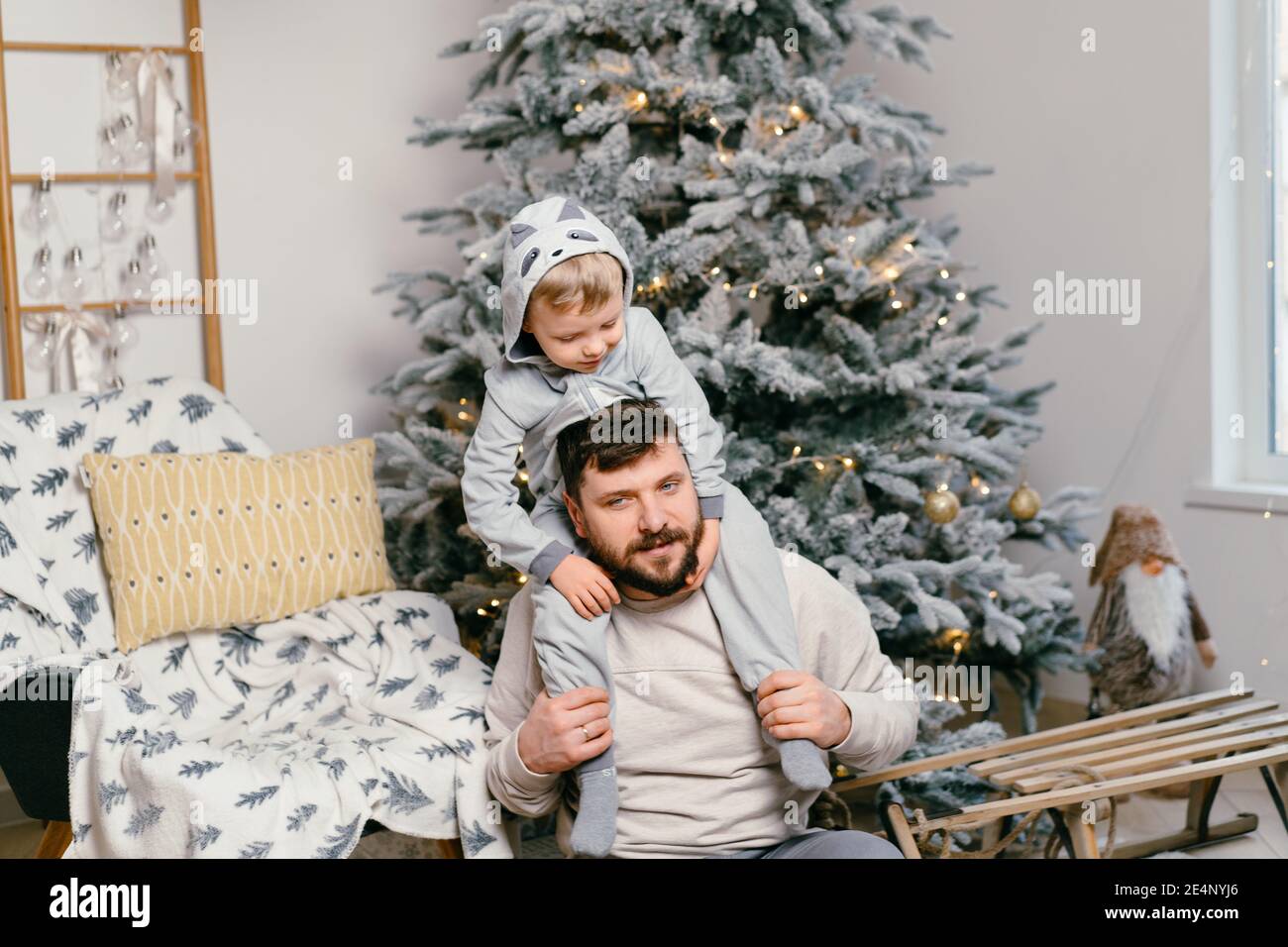 Noël beau père de Noël jouant avec petit fils mignon près Arbre du nouvel an décoré à la maison famille tradition européenne papa et son fils est assis Banque D'Images