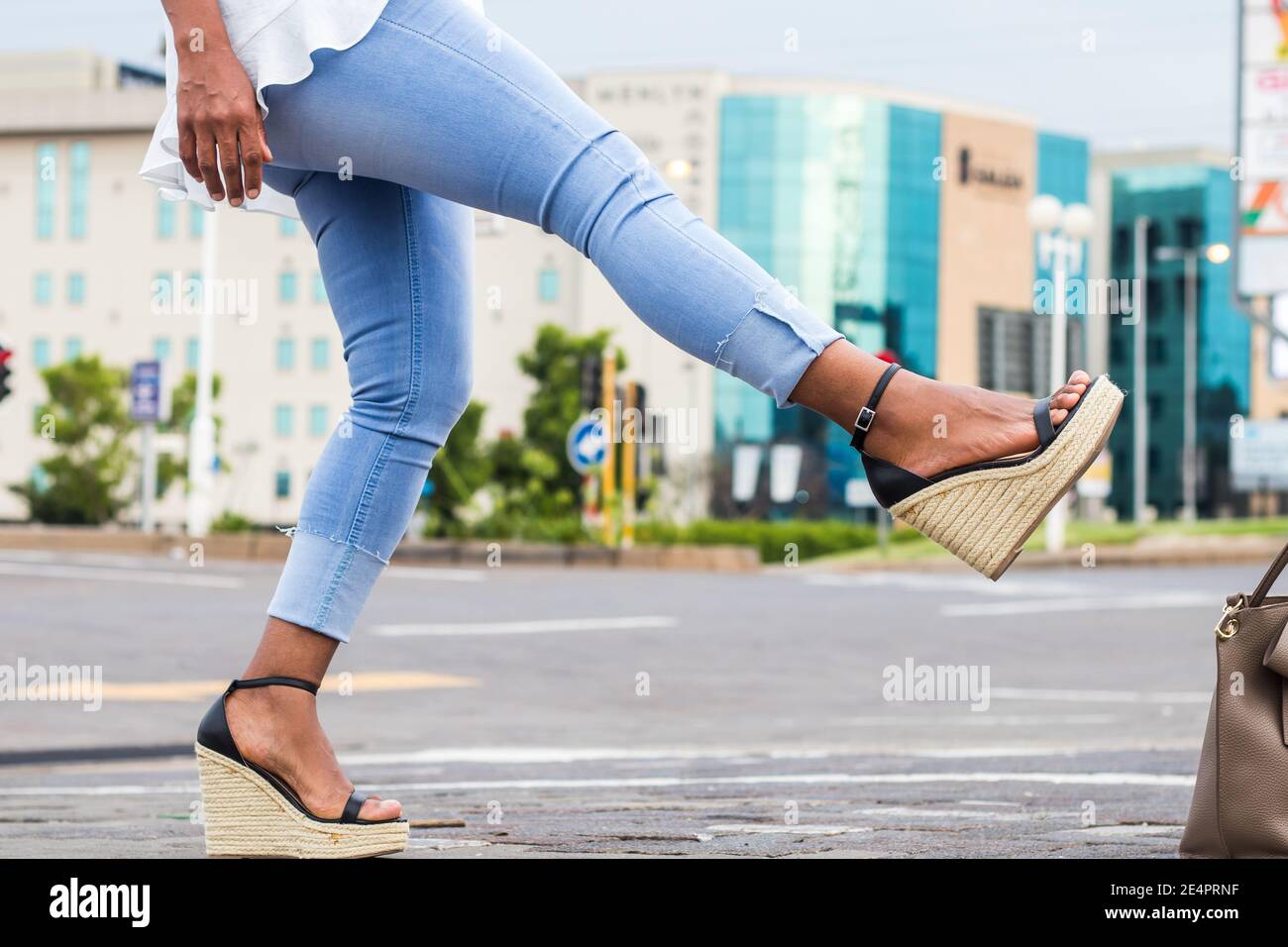 Lady en bleu élégant Jean denim et sandales à talons compensés coup de pied. Banque D'Images