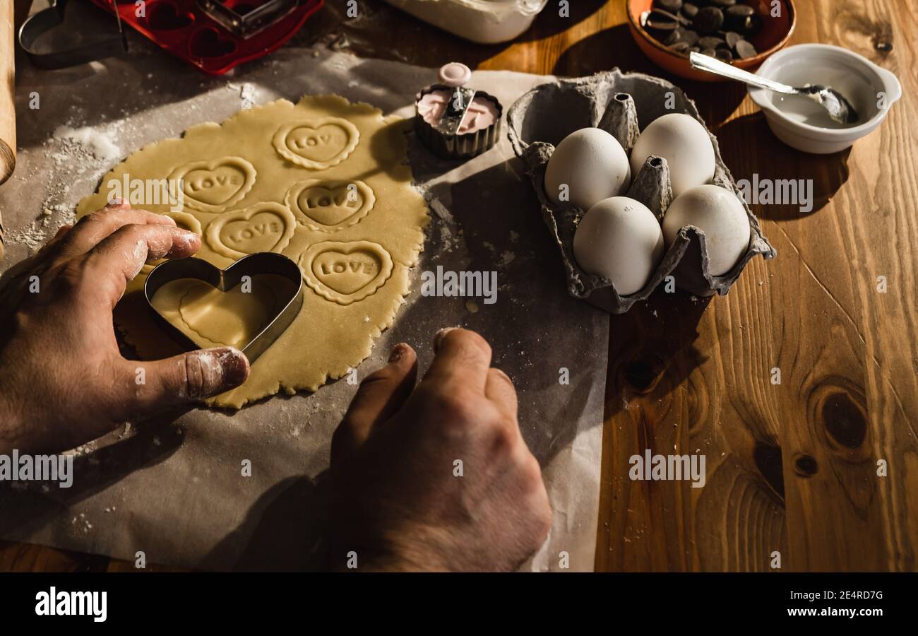 couper la pâte avec un moule. Un homme romantique dans la cuisine prépare des biscuits. Banque D'Images