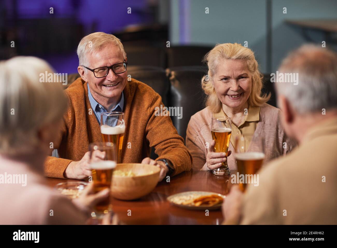 Groupe de personnes âgées souriantes qui boivent de la bière au bar ...