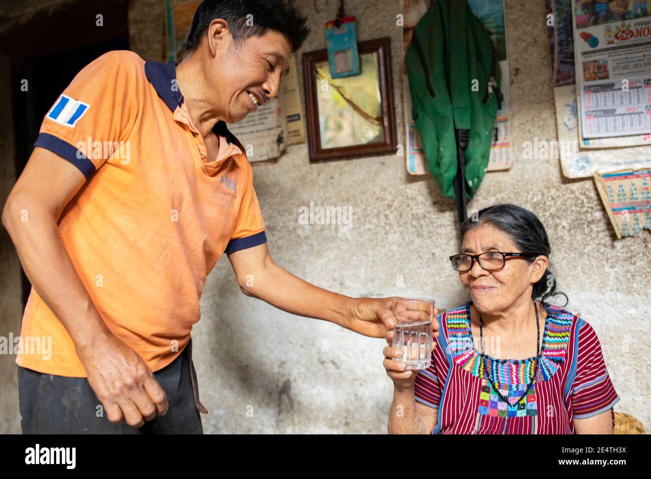 Une femme âgée boit un verre d'eau propre à San Juan la Laguna, au Guatemala. Banque D'Images