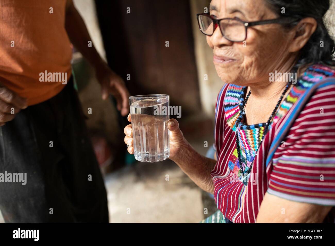 Une femme âgée boit un verre d'eau propre à San Juan la Laguna, Guatemala, Amérique centrale. Banque D'Images