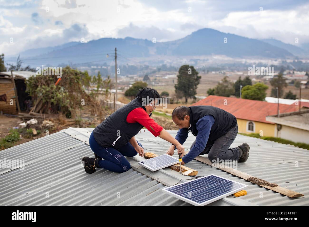 Des techniciens de la société locale d'énergie à but non lucratif installent un nouveau système d'éclairage solaire dans une maison à Cantel, Guatemala, CEN Banque D'Images
