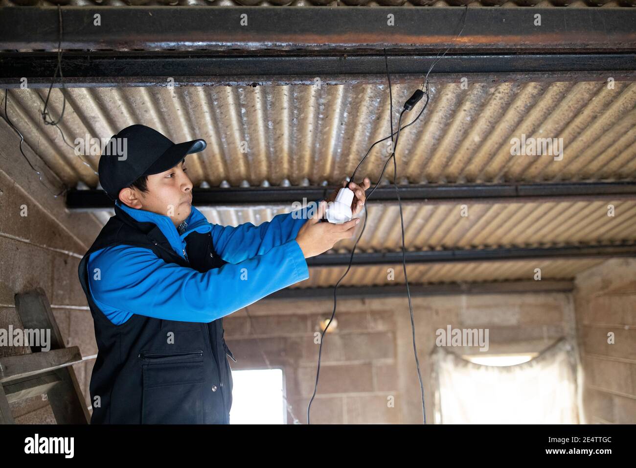 Un technicien de la société locale d'énergie à but non lucratif teste un nouveau système d'éclairage solaire dans une maison à Cantel, au Guatemala, en Amérique centrale. Banque D'Images