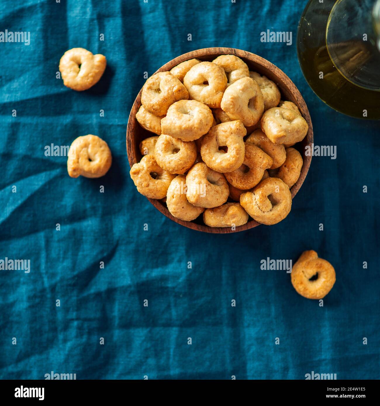 Taralli ou taralini italien traditionnel dans un bol en bois sur fond de serviette bleu foncé. Photo rustique de taralli apéritif avec espace copie. Vue de dessus ou plan de travail. Recadrage carré Banque D'Images