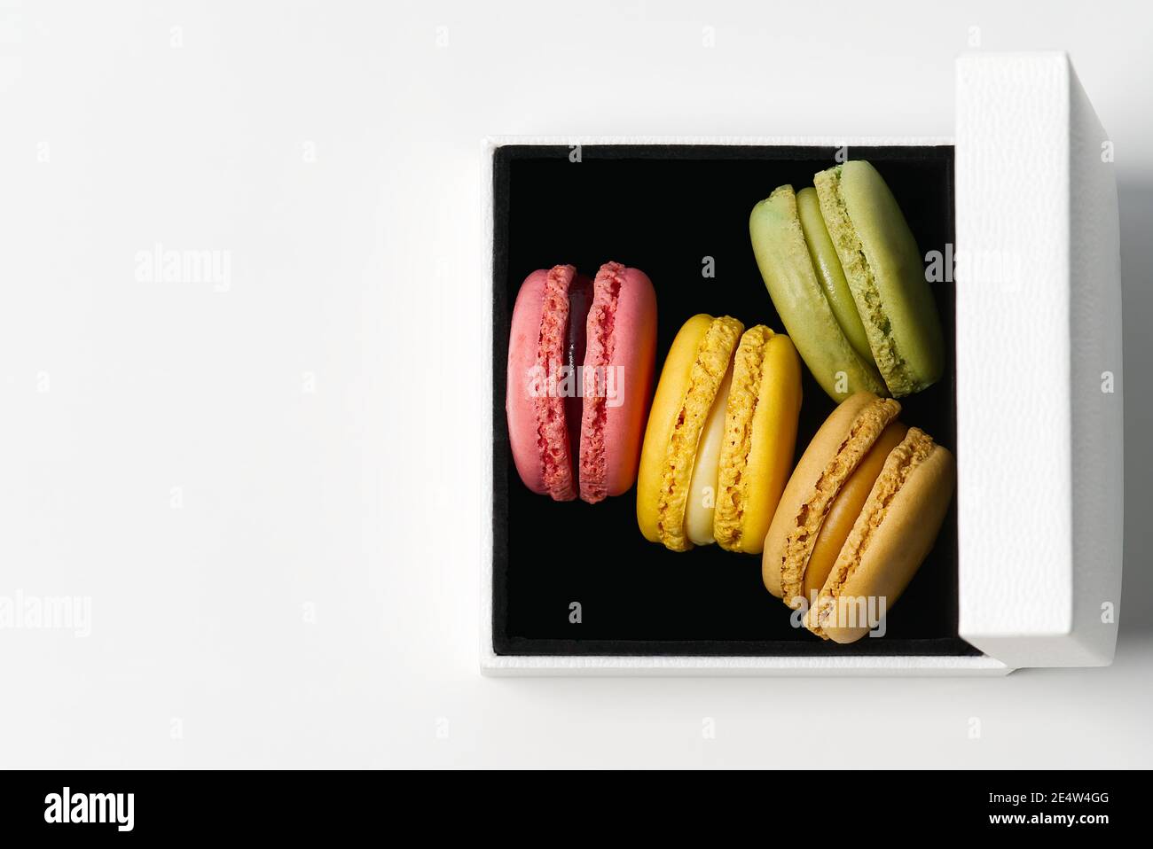 Macarons colorés dans une boîte blanche sur fond blanc Banque D'Images