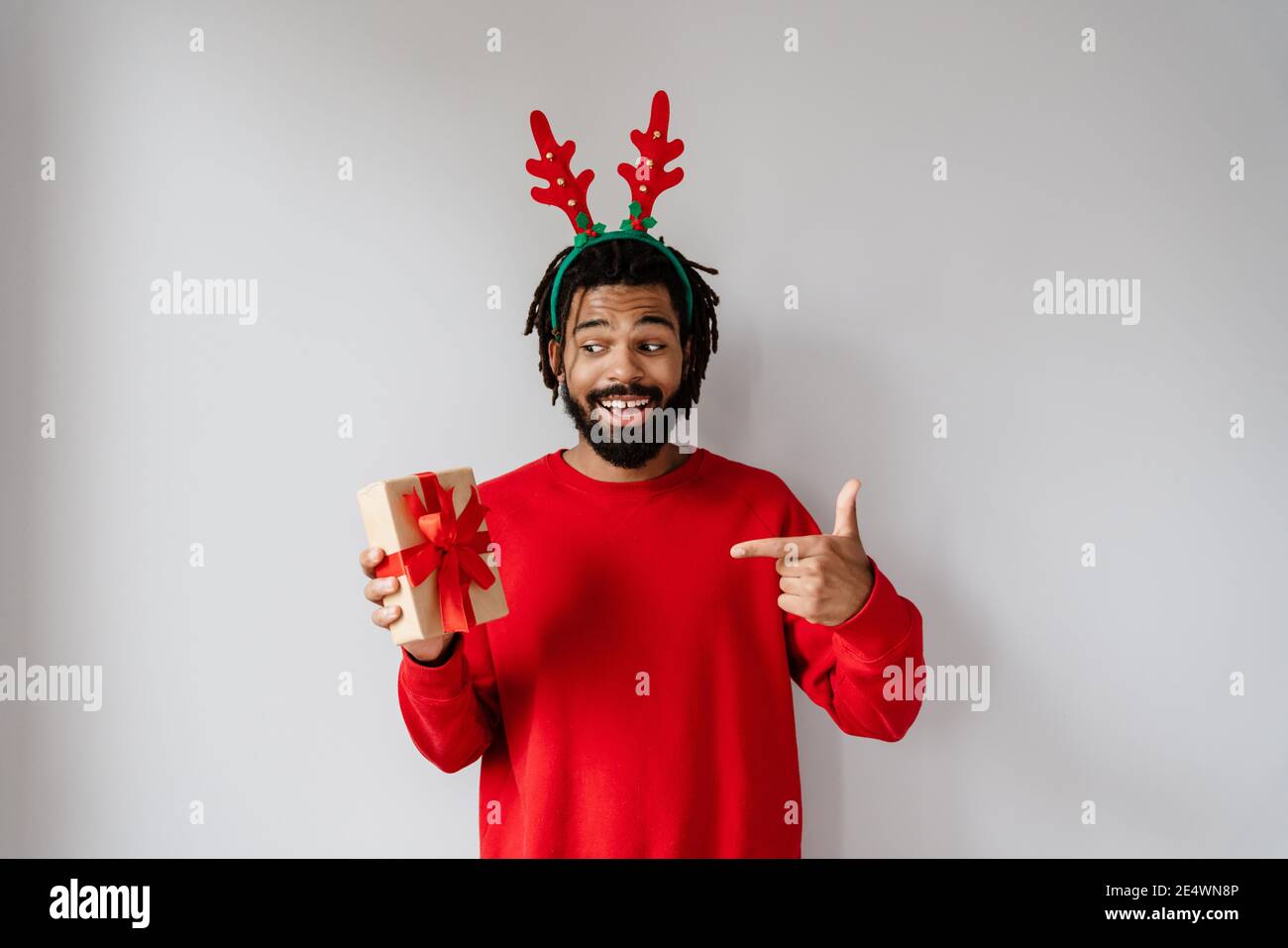 Drôle d'homme afro-américain en tenant et en pointant du doigt vers boîte cadeau isolée sur fond blanc Banque D'Images