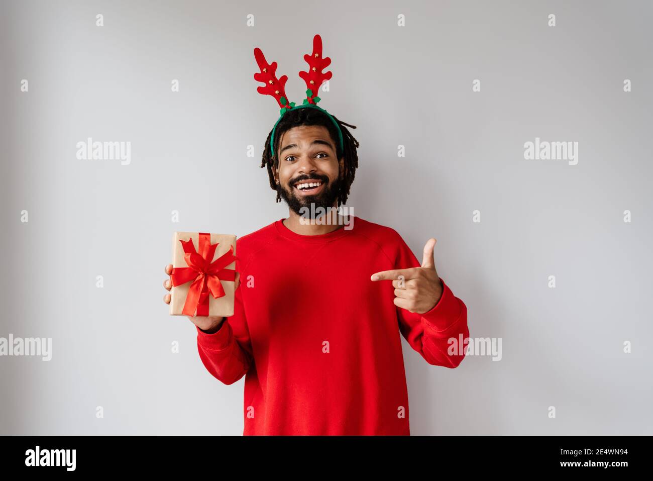 Drôle d'homme afro-américain en tenant et en pointant du doigt vers boîte cadeau isolée sur fond blanc Banque D'Images