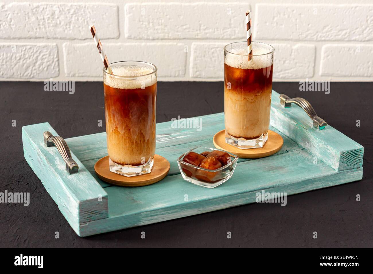 Un café glacé sur un plateau en bois avec de la crème versée dans celui-ci montrant la texture et l'aspect rafraîchissant de la boisson. Banque D'Images