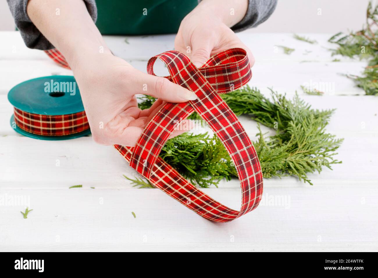 Fleuriste au travail: Comment faire des couronnes de porte de noël traditionnelles avec des brindilles de thuja. Étape par étape, tutoriel. Banque D'Images