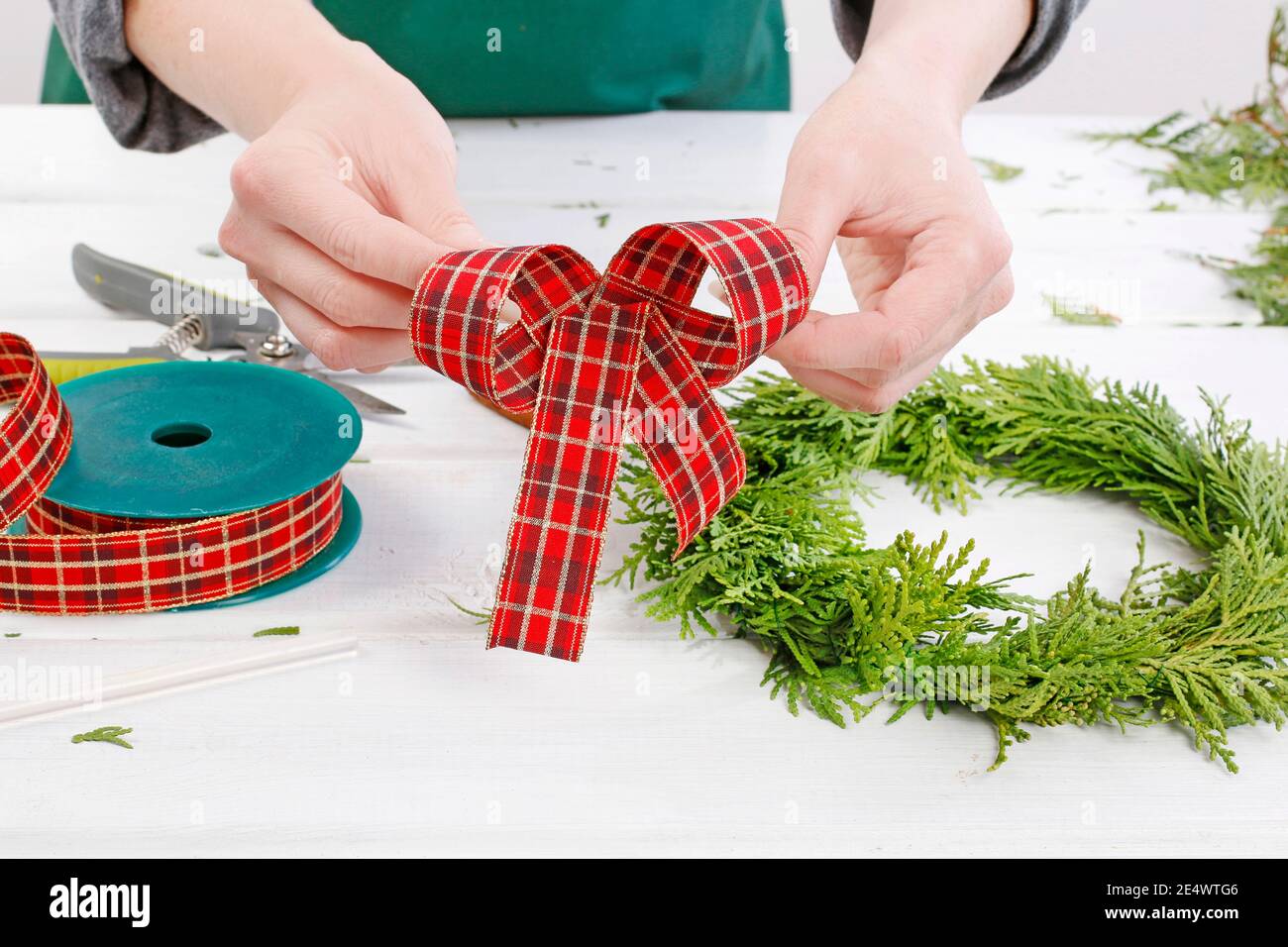 Fleuriste au travail: Comment faire des couronnes de porte de noël traditionnelles avec des brindilles de thuja. Étape par étape, tutoriel. Banque D'Images