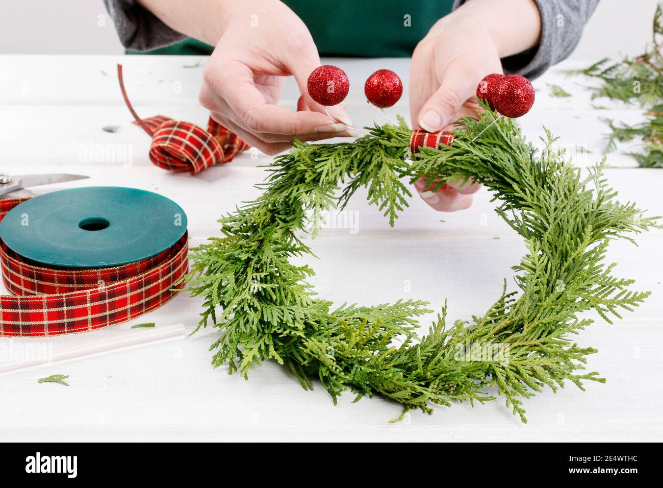 Fleuriste au travail: Comment faire des couronnes de porte de noël traditionnelles avec des brindilles de thuja. Étape par étape, tutoriel. Banque D'Images