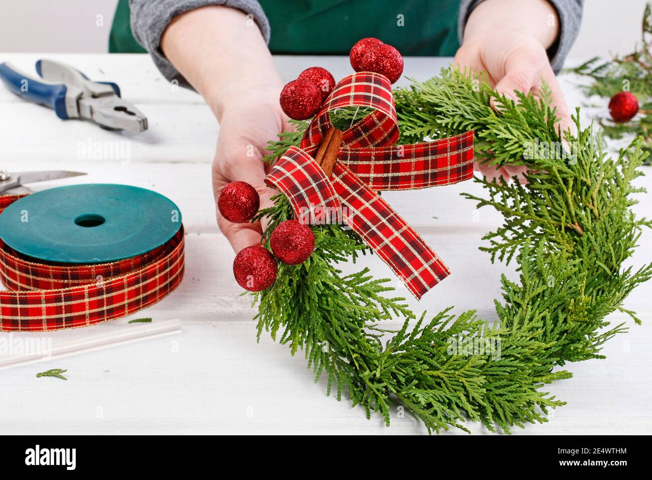 Fleuriste au travail: Comment faire des couronnes de porte de noël traditionnelles avec des brindilles de thuja. Étape par étape, tutoriel. Banque D'Images