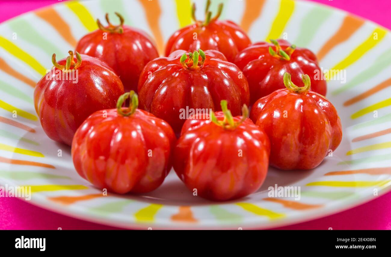 Cerises brésiliennes rouges sur une assiette Banque D'Images