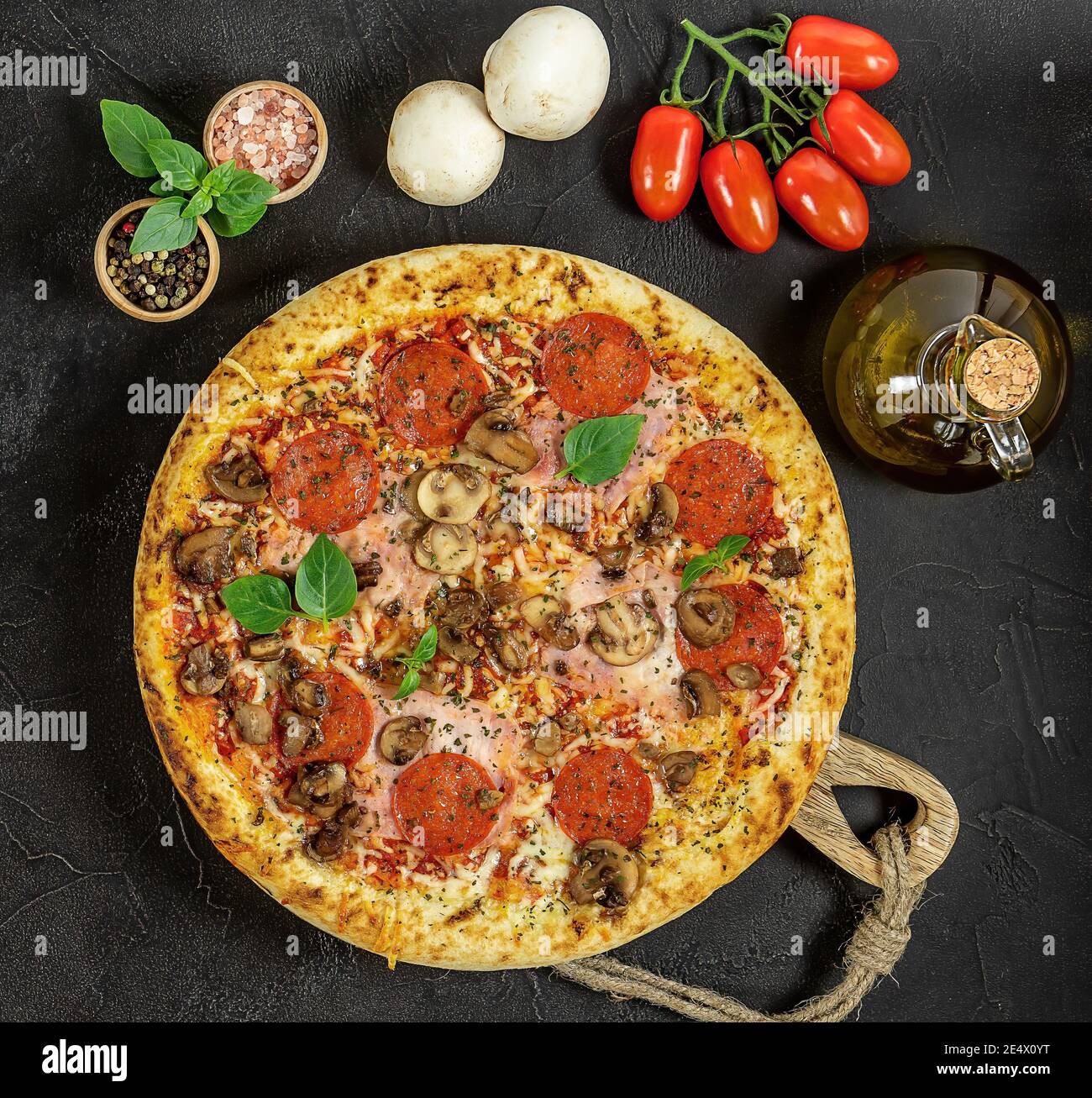 Pizza italienne chaude à Naples avec jambon et champignons sur le noir arrière-plan Banque D'Images