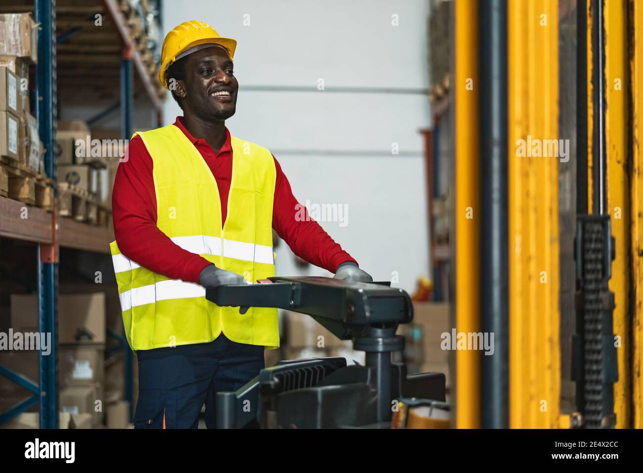 Homme noir travaillant dans un entrepôt avec des boîtes de livraison de chargement de chariot élévateur - concept logistique et industrie Banque D'Images