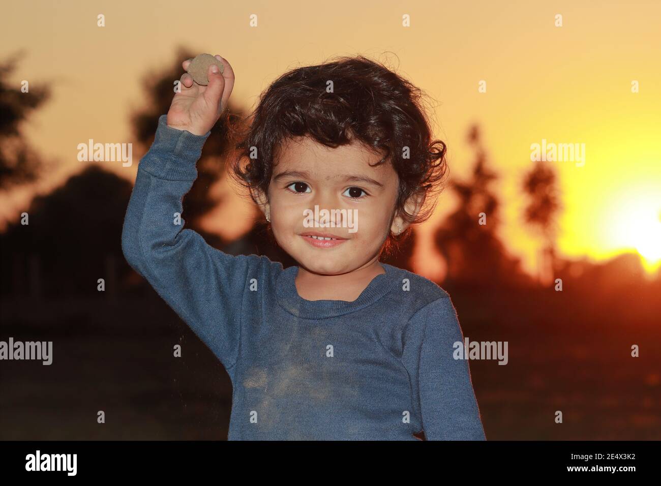 Un beau petit enfant indien hindou souriant en regardant la caméra avec la pierre de terre a levé dans son hand.india Banque D'Images