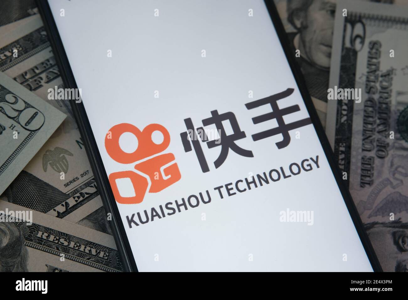 Stafford, Royaume-Uni - janvier 25 2021 : logo de l'application Kuaishou visible sur l'écran du smartphone et billets en dollars flous en arrière-plan. Concept de Banque D'Images