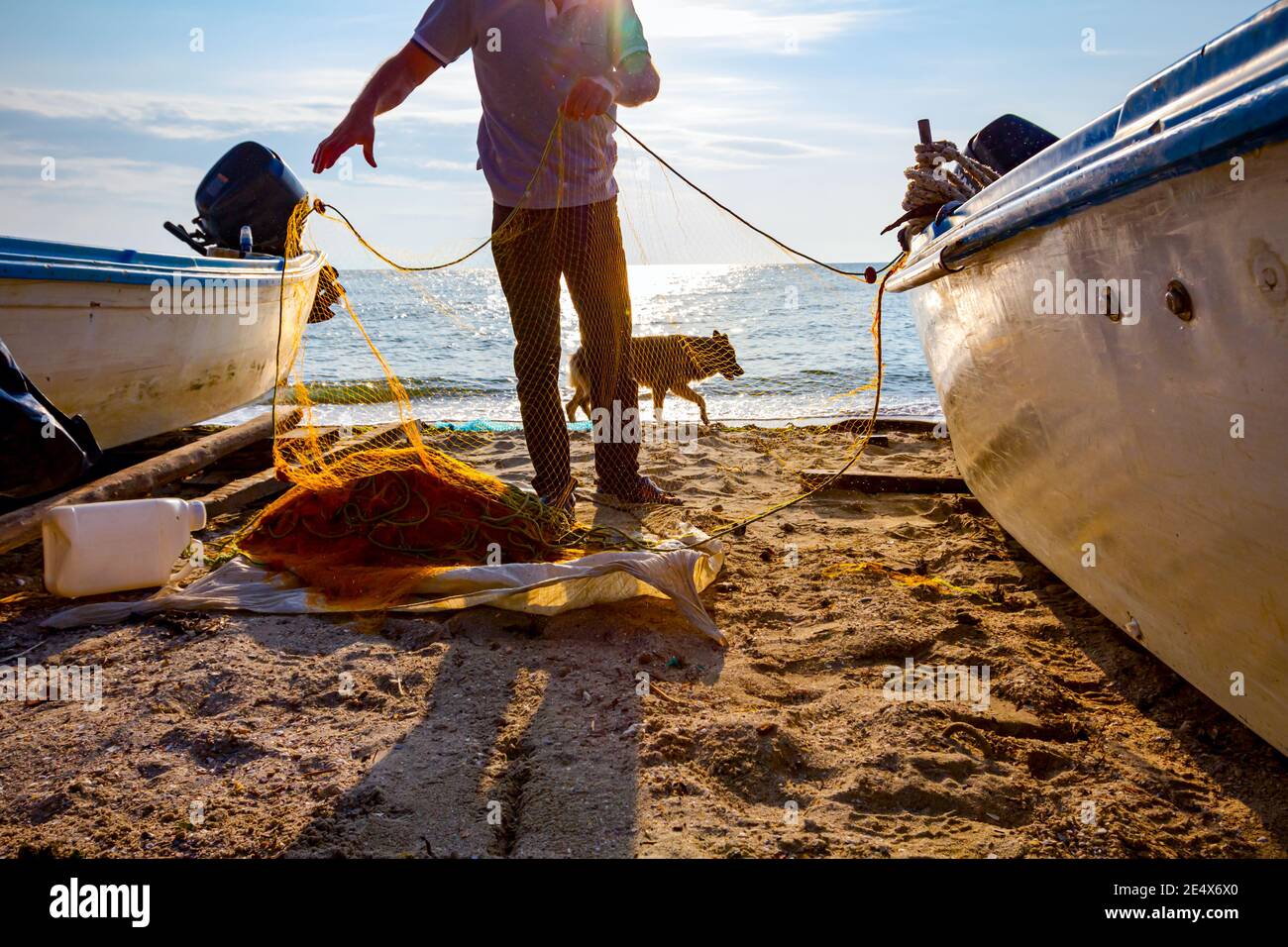 Le pêcheur prend du poisson du filet et prépare sa prochaine pêche à la ligne. Banque D'Images
