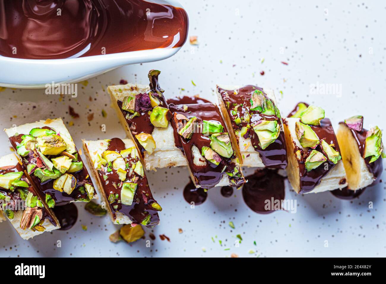 Sushi sucré à la banane avec chocolat et noix, fond blanc. Concept de dessert végétalien. Banque D'Images