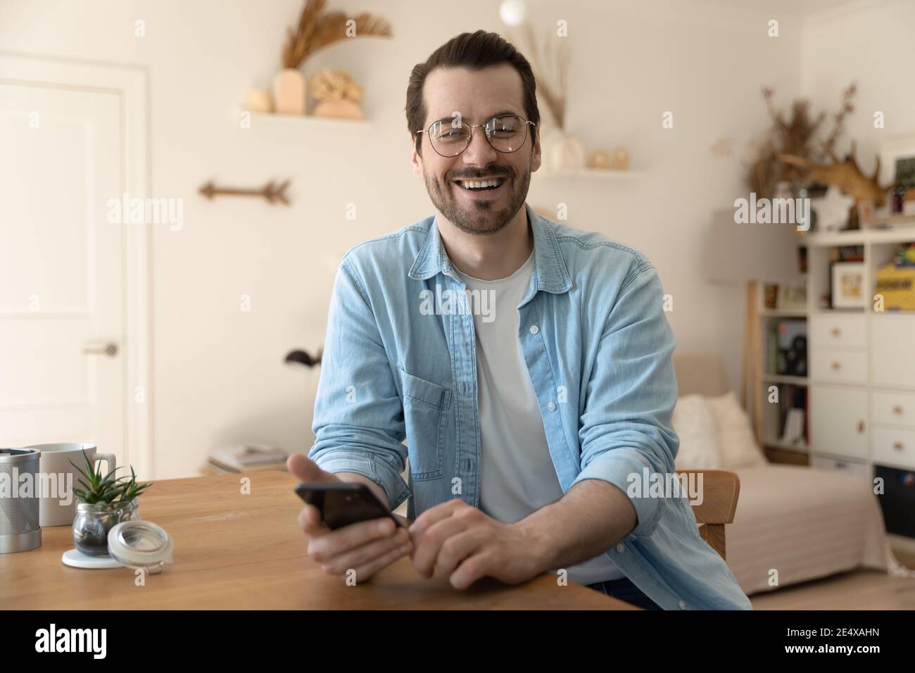 Portrait d'un jeune homme en train de rire distrait de l'écran du smartphone Banque D'Images