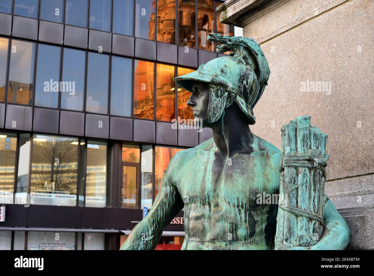 Ancienne sculpture en bronze d'une allégorie masculine du monument Bismarck dans le centre-ville de Düsseldorf, dévoilée en 1899. Bâtiment moderne en arrière-plan. Banque D'Images