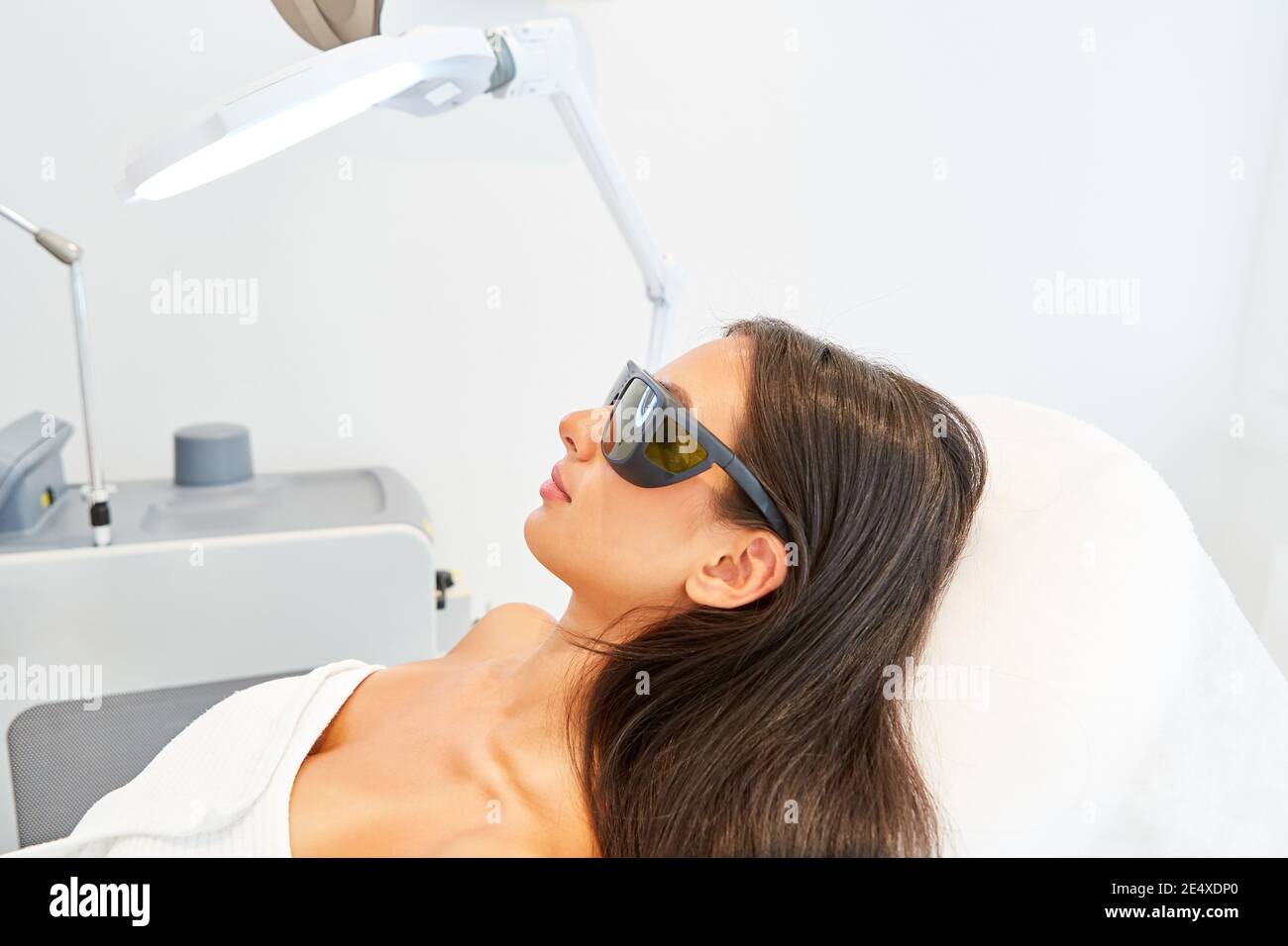 Femme avec lunettes de protection pendant le traitement laser dans le clinique de beauté Banque D'Images