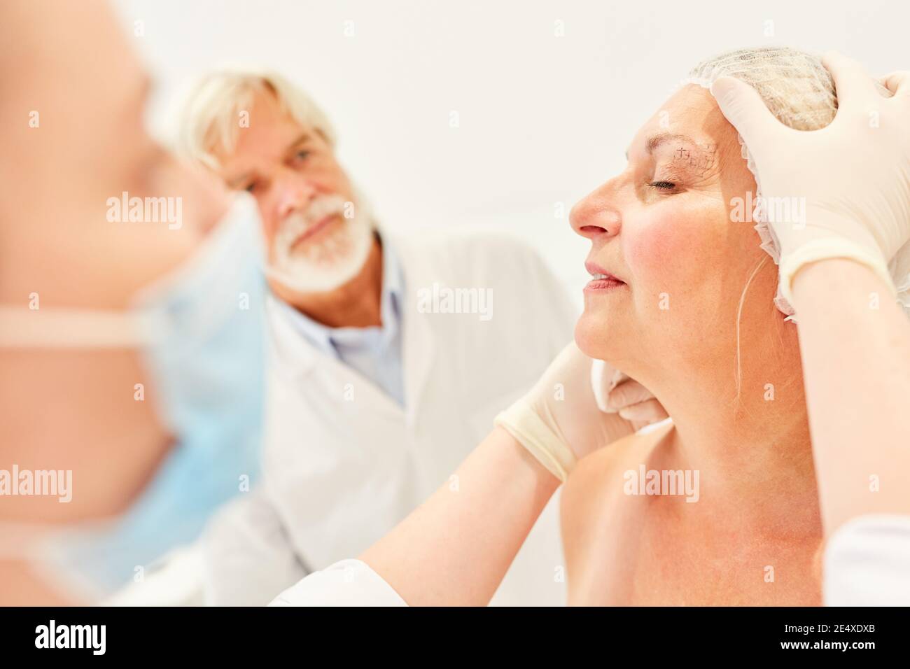 Spécialistes en chirurgie esthétique vérifiant une correction de paupière dans un femme âgée Banque D'Images