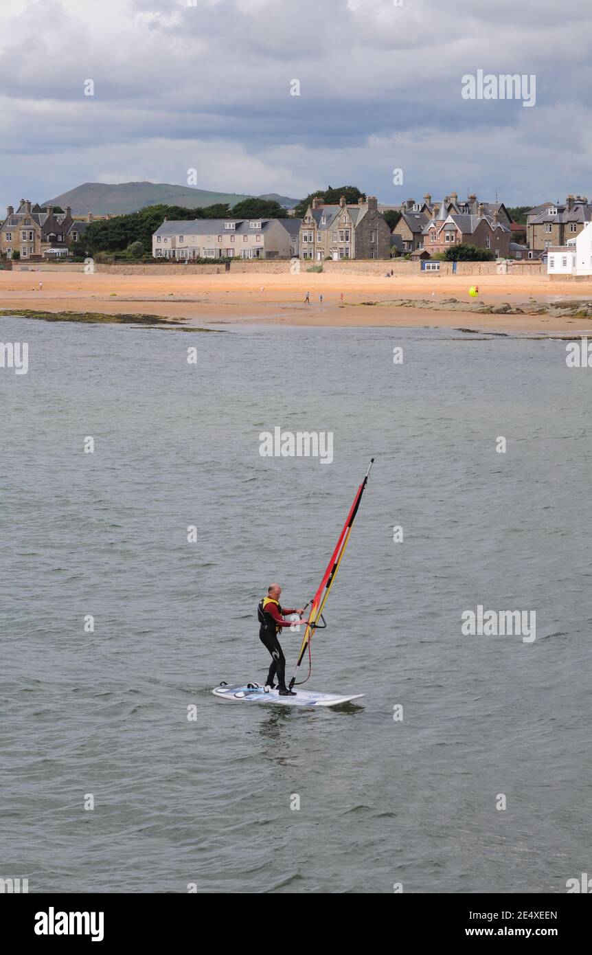 Un homme sur un voilier au large de la plage à Elie dans le Neuk est de Fife, Écosse, Royaume-Uni, Europe Banque D'Images
