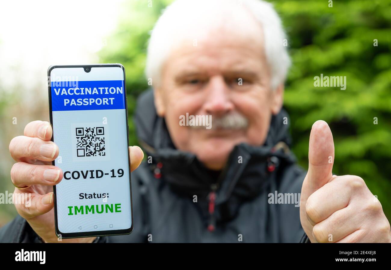 Homme âgé présentant un passeport de vaccination sur un téléphone portable, ce qui indique une vaccination contre le covid-19. Banque D'Images