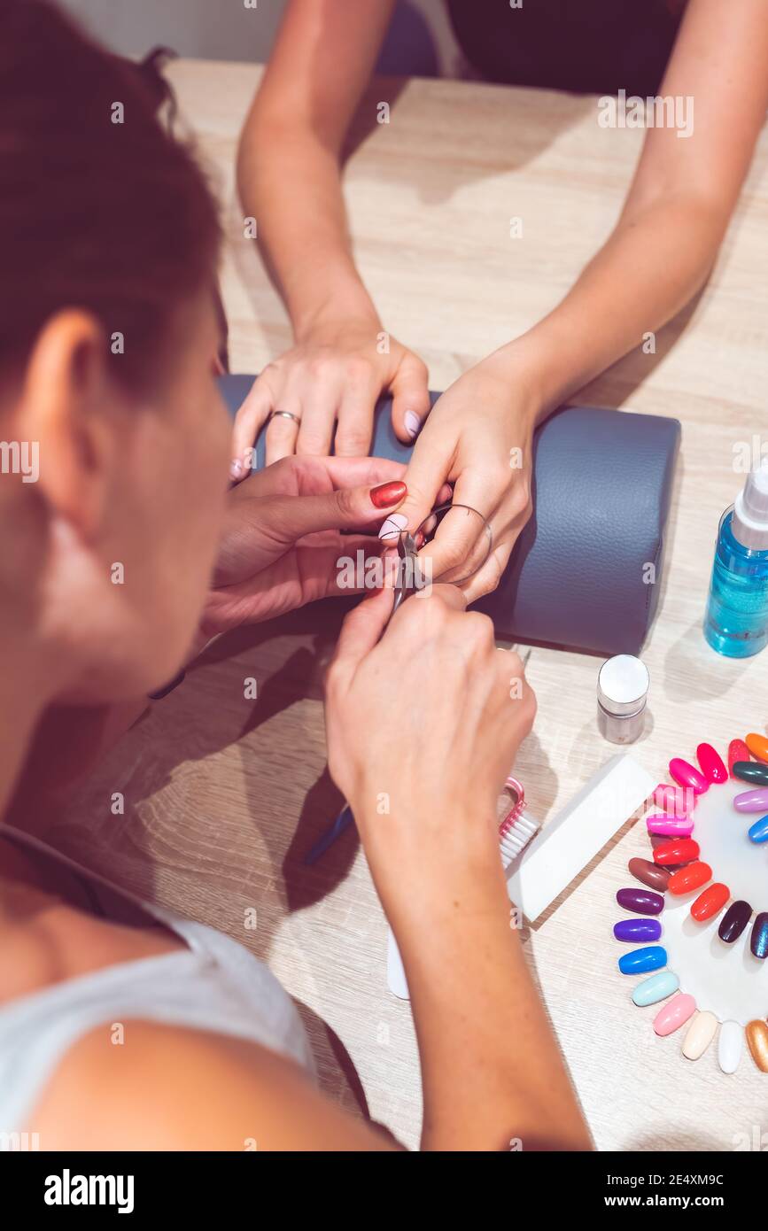 Gros plan des mains et des ongles de deux femmes. Concept de manucure. Concentration sélective sur un clou en cours de travail. Banque D'Images