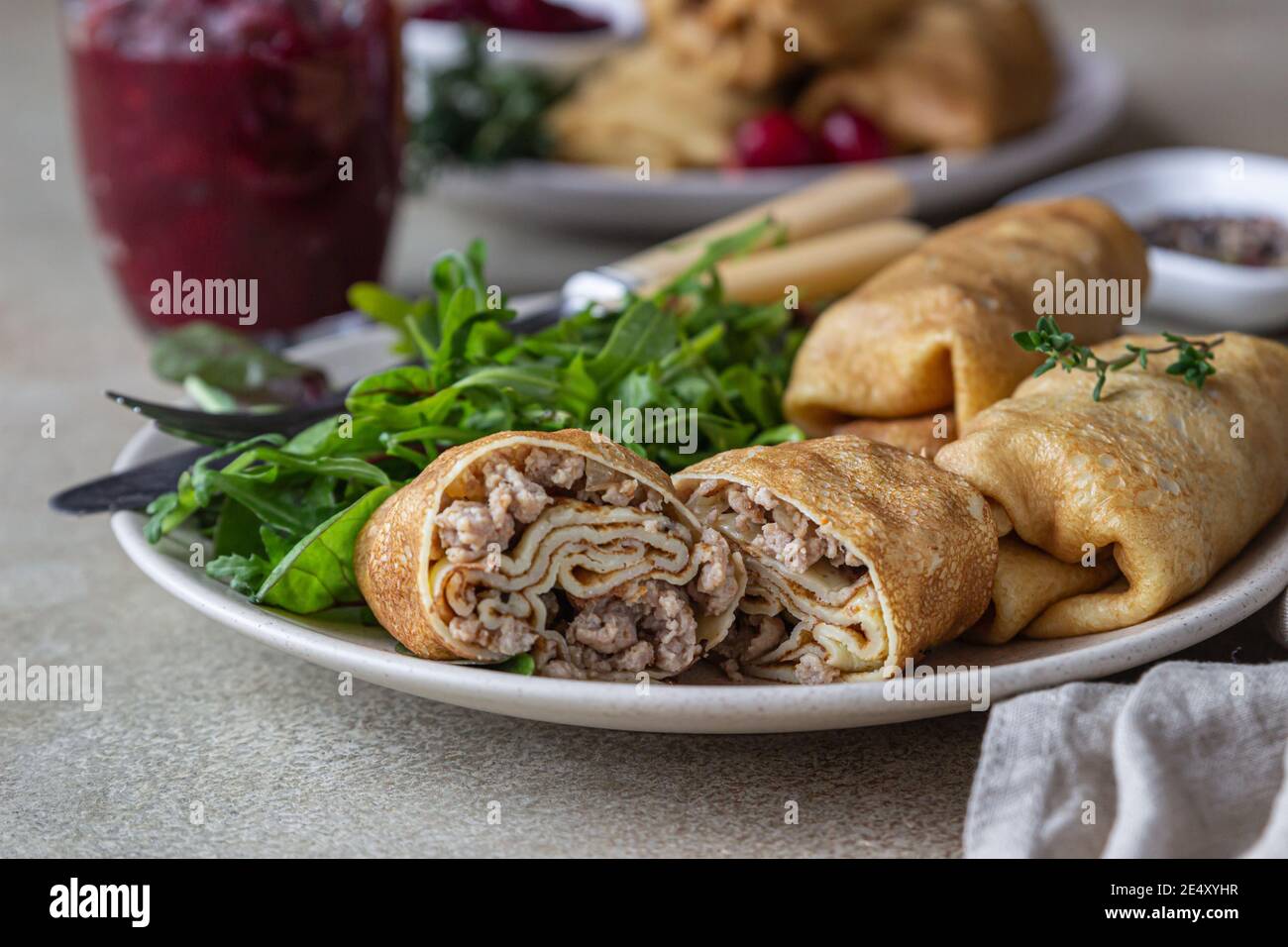 Crêpes fines farcies faites maison ou crêpes à la viande, sauce épicée aux canneberges et à l'arugula, fond de pierre légère. Cuisine russe traditionnelle pour Masleni Banque D'Images