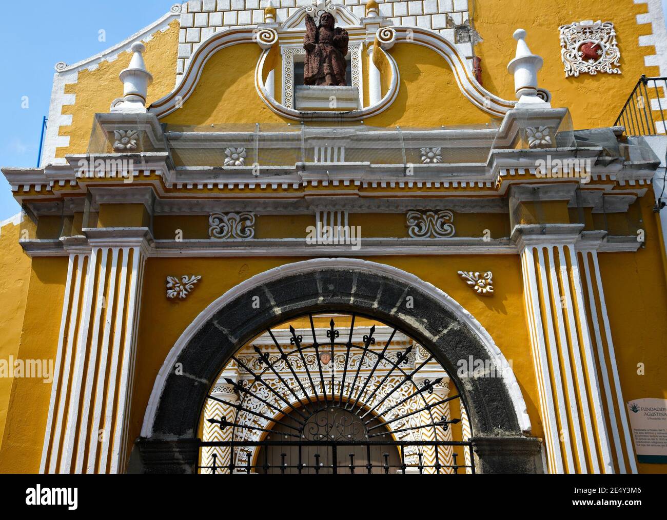 Entrée voûtée de l'ancien couvent de San Agustin de style baroque avec le mur ocre typique et les gravures de la façade en pierre à Atlixco, Puebla Mexique. Banque D'Images