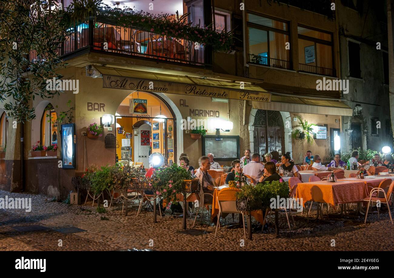 Vacanciers dînant en plein air devant un bar de Malcesine, sur la rive est du lac de Garde, dans la région de Vénétie en Italie. Banque D'Images