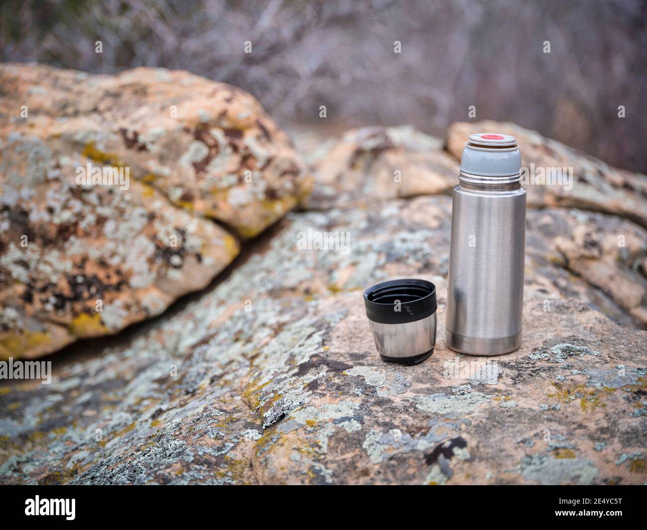 petite bouteille de thermos en acier et thé chaud sur un rocher pendant la saison froide de randonnée Banque D'Images