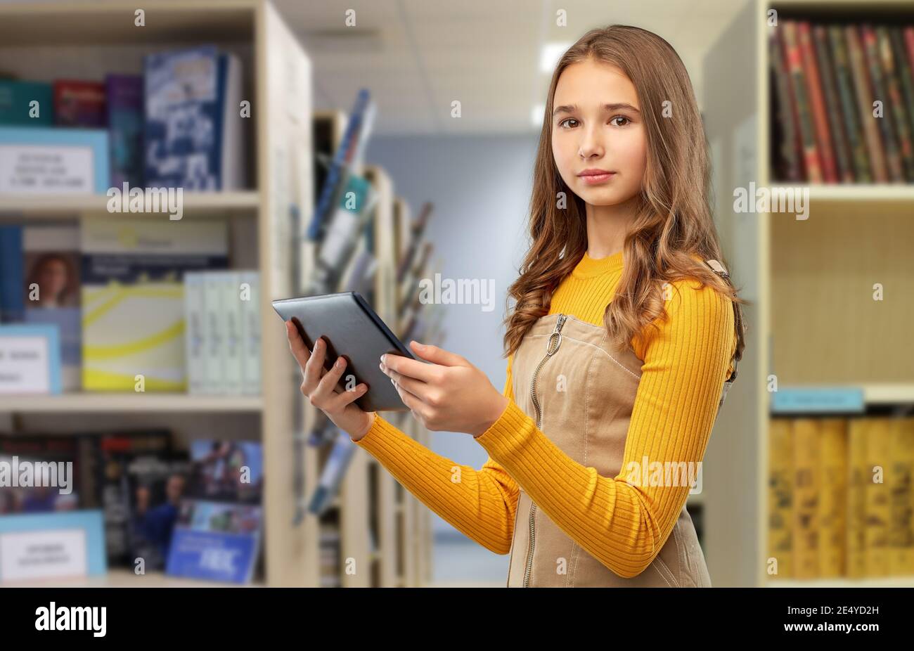 une jeune fille étudiante utilisant une tablette informatique à la bibliothèque Banque D'Images