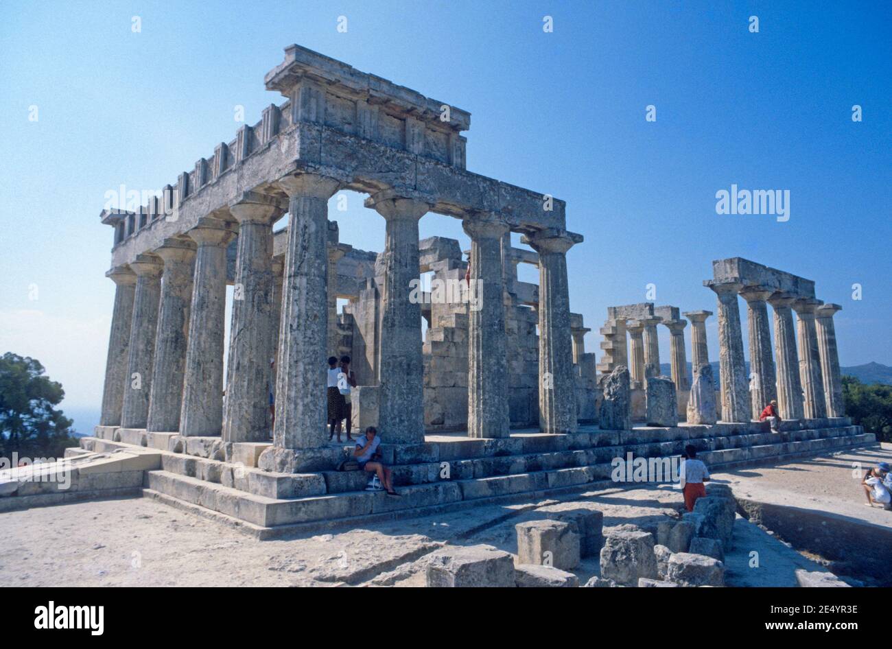 1986 Grèce Temple d'Aphaia Aegina le Temple d'Aphaia ou Afea se trouve dans un complexe de sanctuaire dédié à la déesse Aphaia sur l'île grecque d'Aegina dans le golfe Saronique. Autrefois connu sous le nom de Temple de Jupiter Panhellenius, le temple dorique est maintenant reconnu comme étant dédié à la déesse mère Aphaia, touristes lors d'une visite guidée appréciant la vue du Temple grec, Aegina Grèce eu Europe Banque D'Images