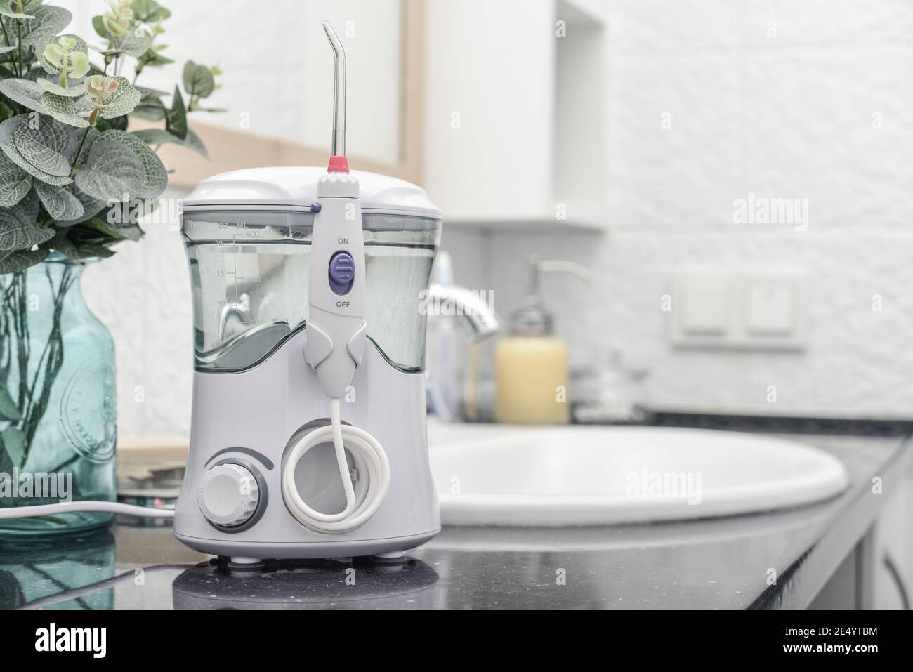 Irrigateur buccal électrique dans la salle de bains carrelée de blanc Banque D'Images