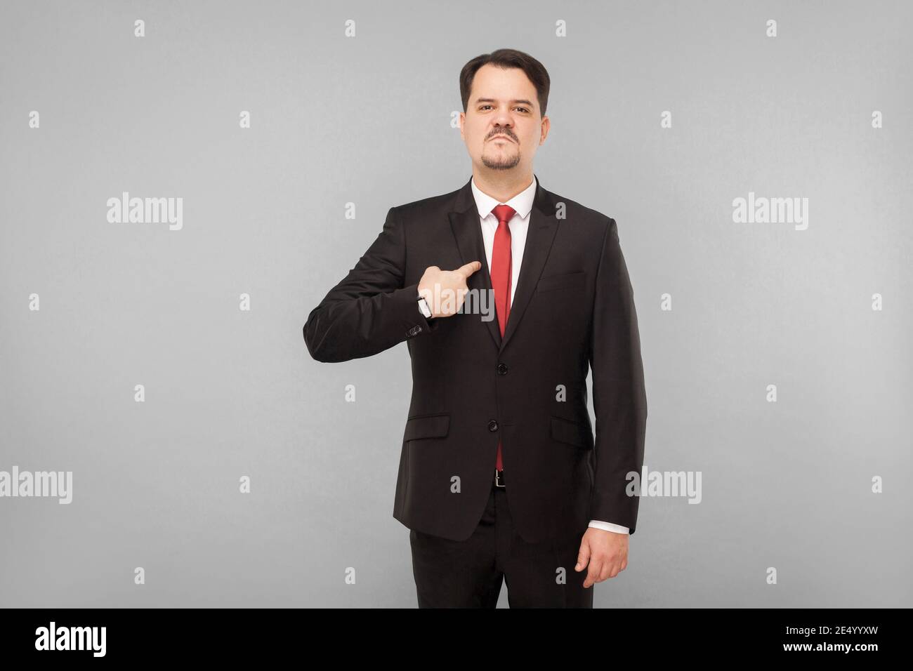 Homme de vêtements classiques se pointant vers l'appareil photo. Je l'ai fait et je suis fier de lui. Prise de vue en studio. Isolé sur fond gris. Beau homme d'affaires wi Banque D'Images