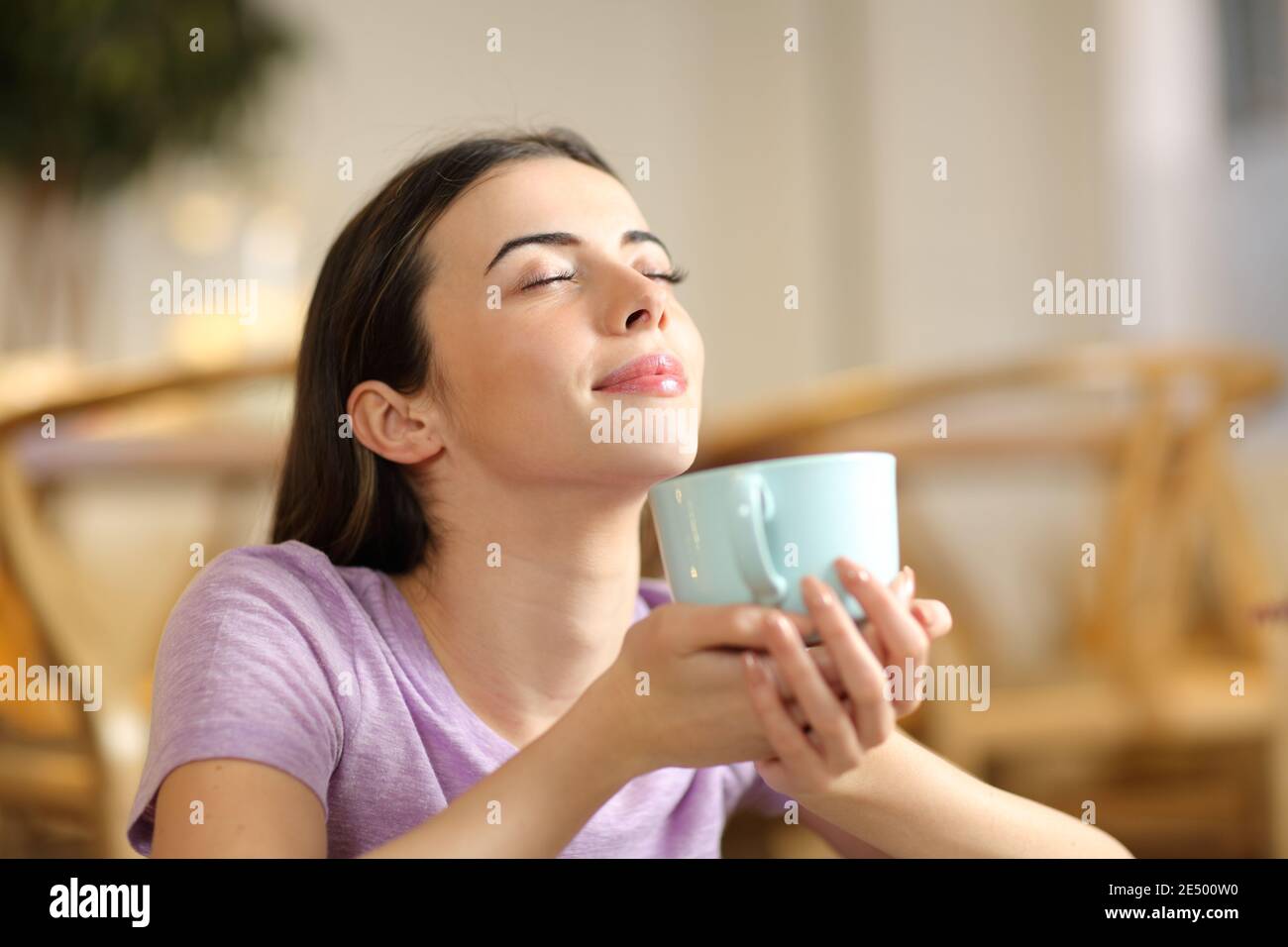 Une femme heureuse sent le café en respirant de l'air frais à la maison Banque D'Images