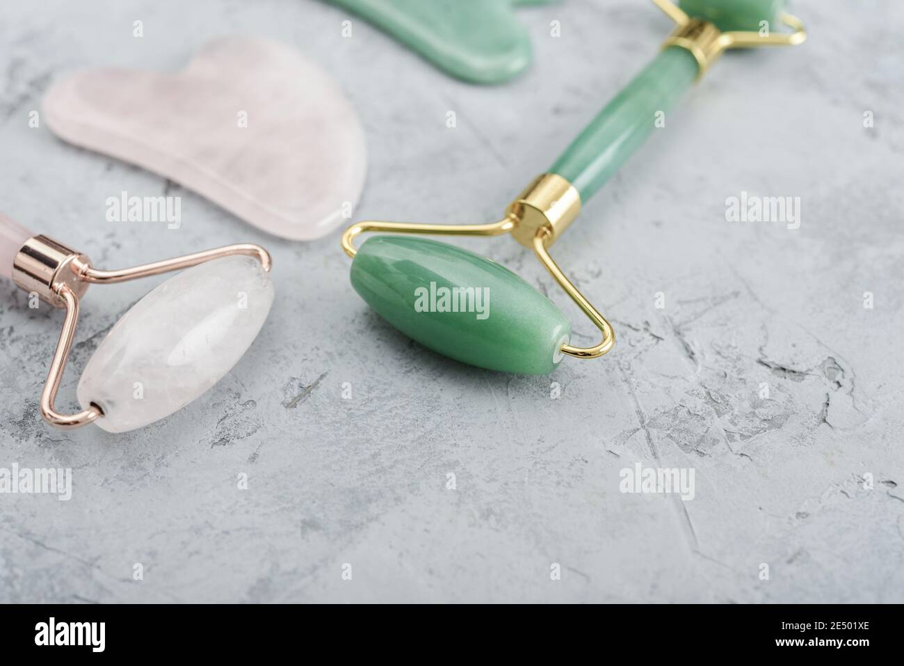 Rouleaux de massage de jade facial et masseurs de gua sha fabriqués à partir de jade naturelle et pierre de quartz rose sur fond gris Banque D'Images