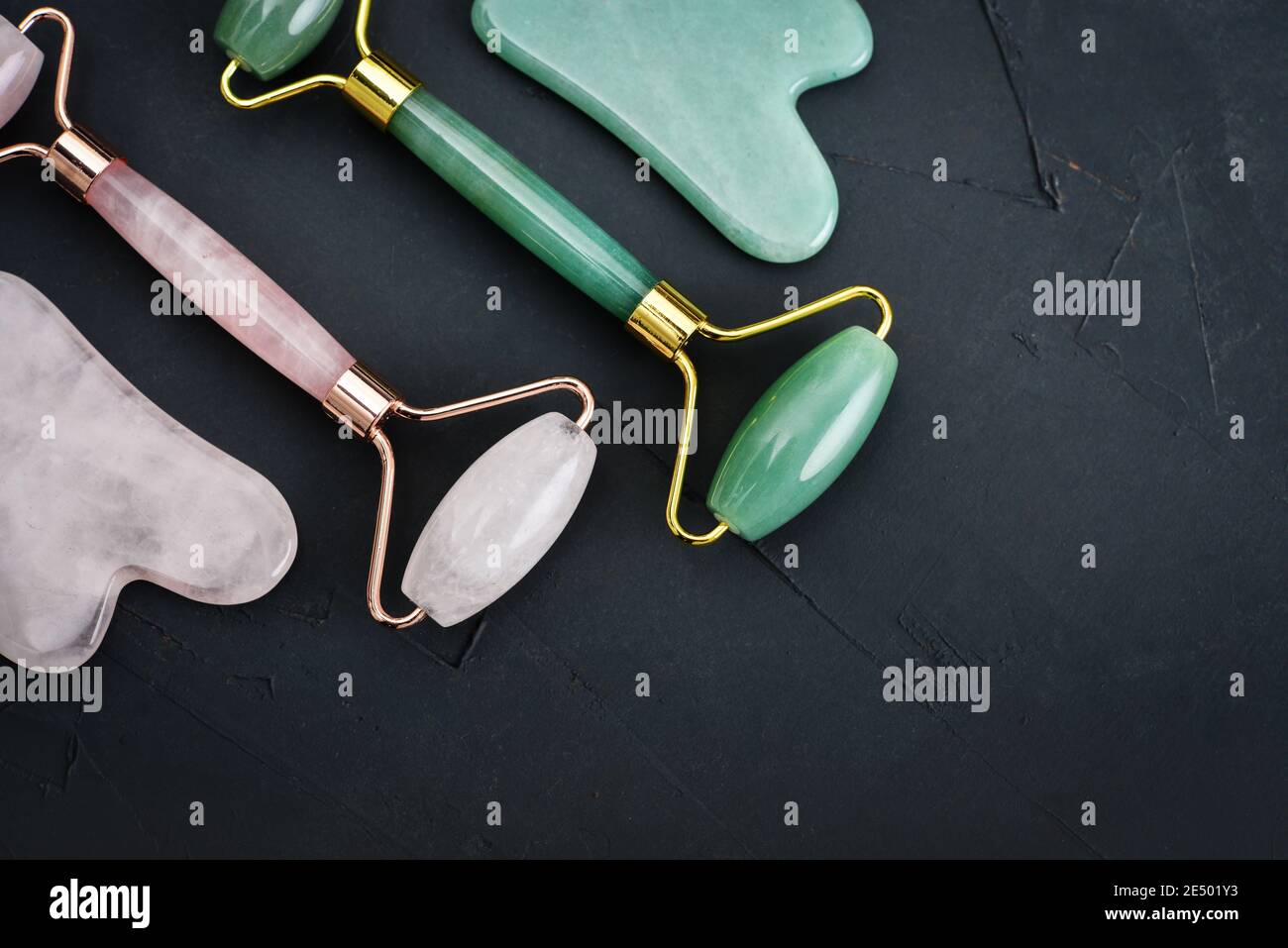 Rouleaux de massage de jade facial et masseurs de gua sha en jade naturel et en pierre de quartz rose sur fond noir, vue du dessus Banque D'Images