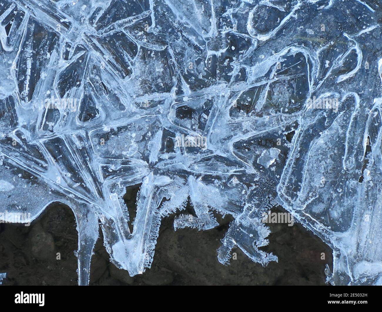 Photo abstraite de cristaux de glace glacés dans de belles formes formées le long de bassins d'eau sombre profonde. Banque D'Images