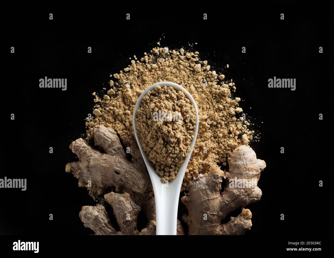 Racine de gingembre et poudre de gingembre dans une cuillère isolée sur fond noir, vue de dessus. Banque D'Images